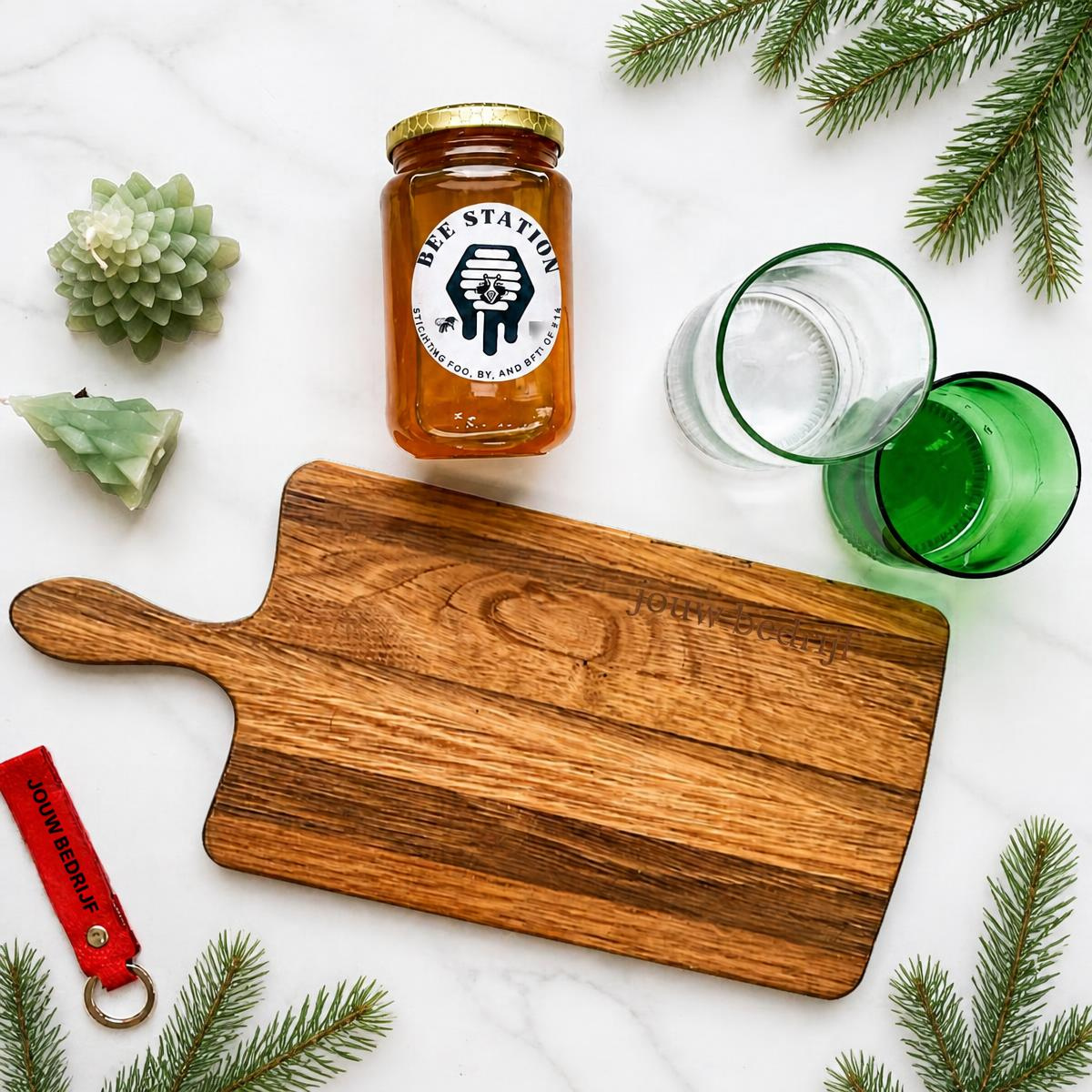 Inhoud van het circulaire kerstpakket: een houten serveerplank, glazen, honing, kaarsen en sleutelhanger
